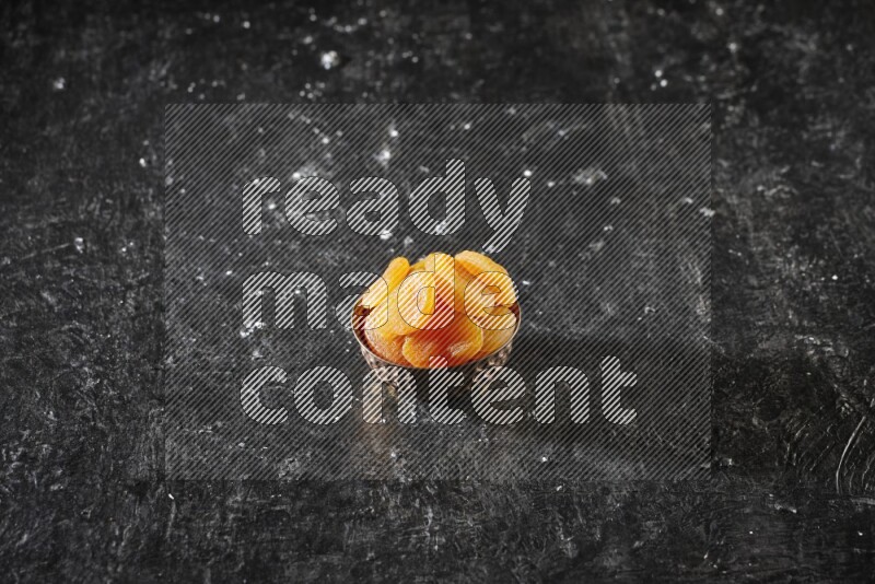 Dried fruits in a metal bowl in a dark setup