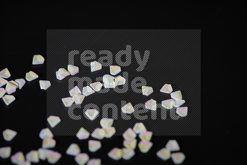 Colorful plastic shards for decoration scattered on a black background