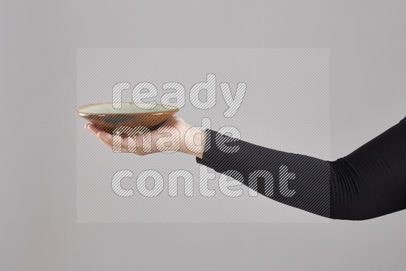 A woman in black abaya holding different pottery essentials in different positions