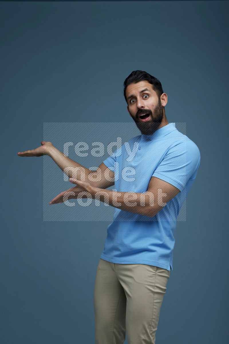 A man pointing  in a blue background wearing a Blue shirt
