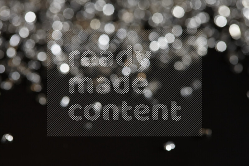 قطع زجاجية فضية لامعة متناثرة على خلفية سوداء