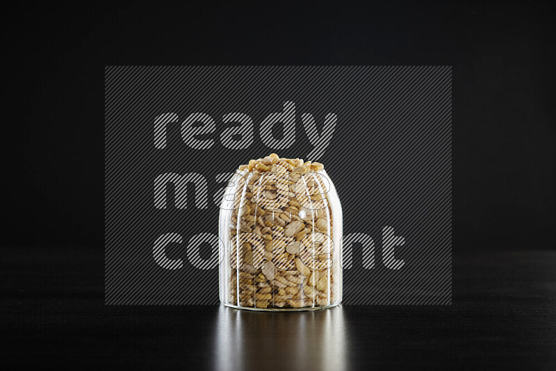 Crushed beans in a glass jar on black background