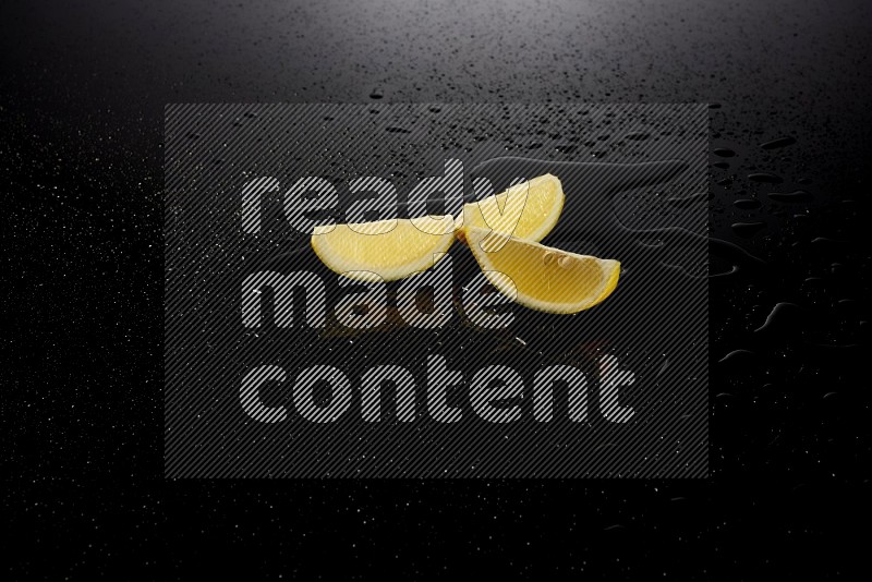 Lemon wedges with water drops, and droplets on black background