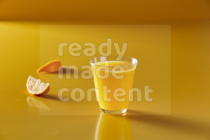 glass of orange juice on yellow background