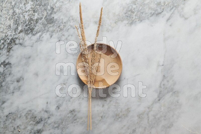 Wheat stalks on multicolored pottery plate on grey marble background
