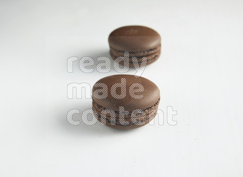 45º Shot of two Brown Dark Chocolate macarons on white background