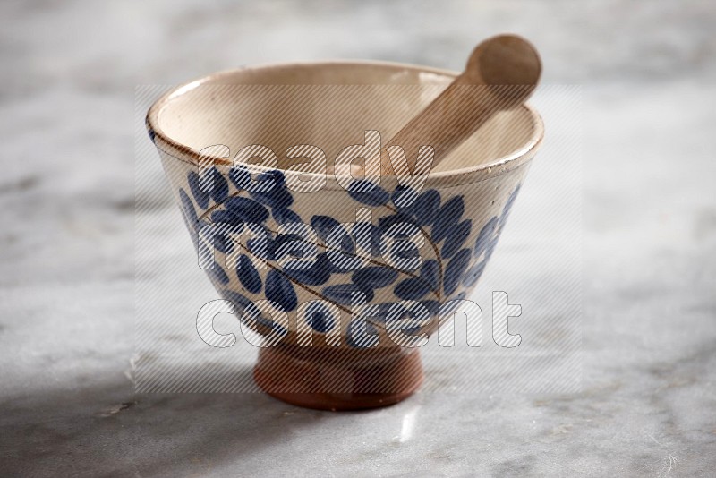 Decorative Pottery Bowl with wooden honey handle in it, on grey marble flooring, 15 degree angle