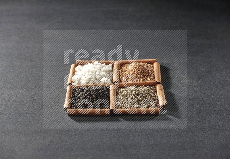 4 squares of cinnamon sticks full of black pepper, white pepper, white salt and mustard seeds on black flooring