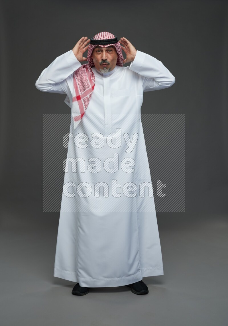 Saudi man with shomag Standing Interacting with the camera on gray background