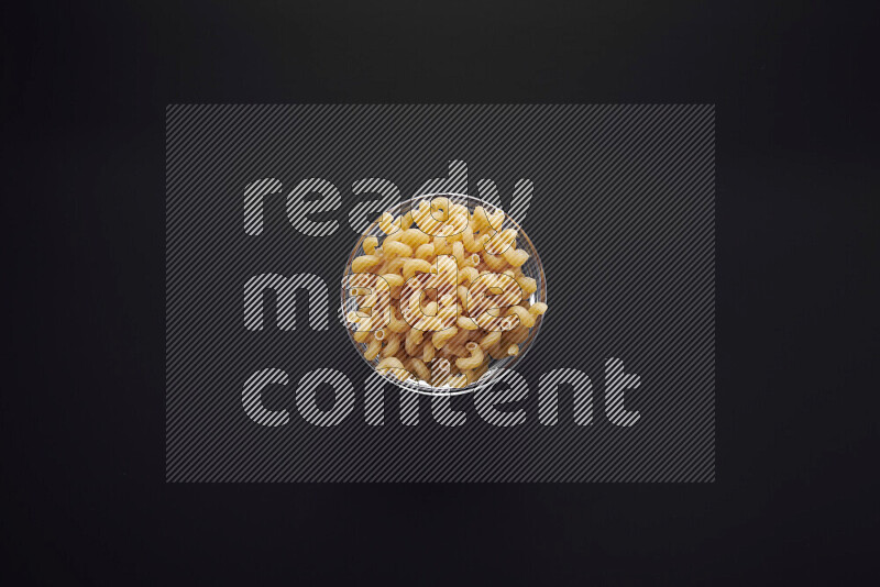 Twist pasta in a glass bowl on black background