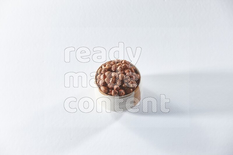 A beige ceramic bowl full of peeled hazelnuts on a white background in different angles