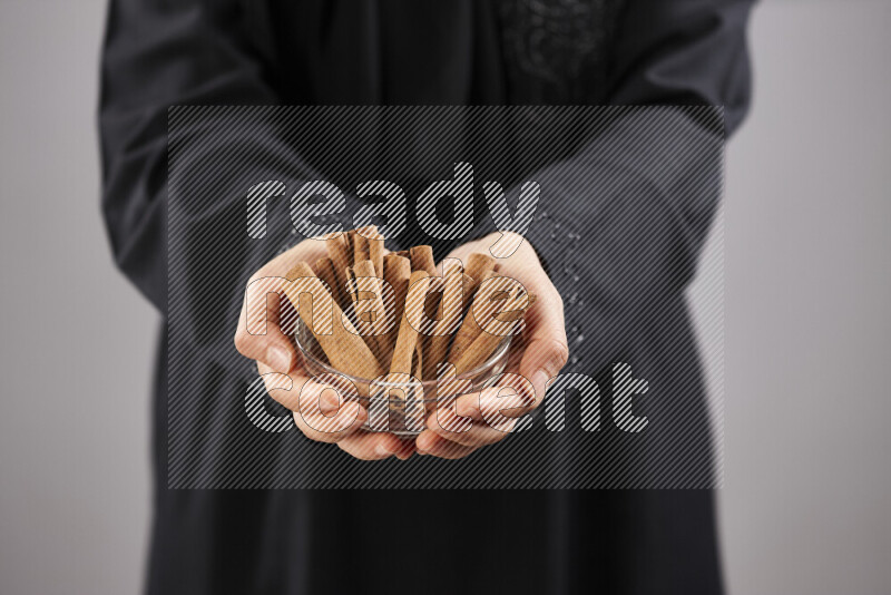 Woman in abaya holding different kinds of spices in different positions