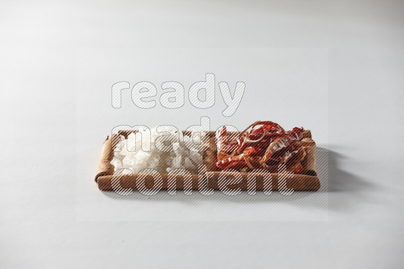 مربعان من أعواد القرفة ممتلئان بالفلفل الحار المجفف والملح الأبيض علي خلفية بيضاء