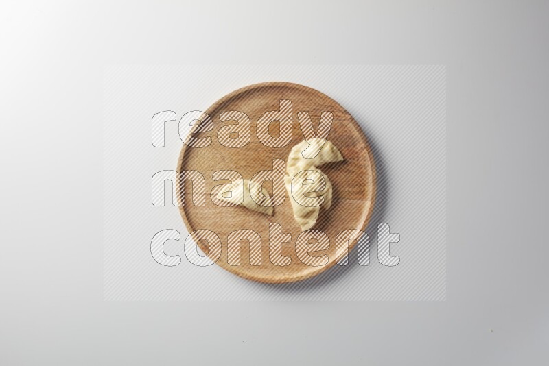 Four Sambosas on a wooden round plate on a white background