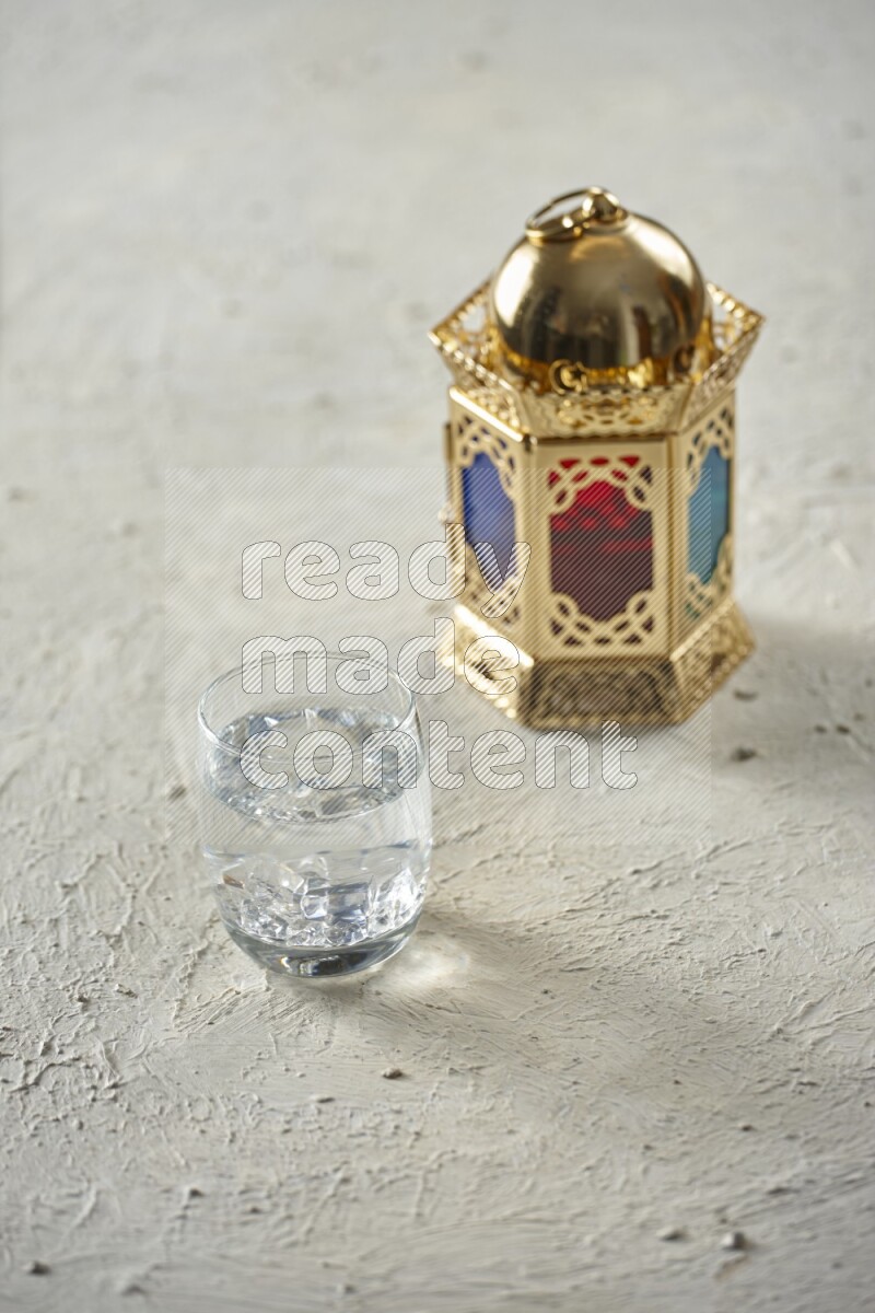 A golden lantern with different drinks, dates, nuts, prayer beads and quran on textured white background