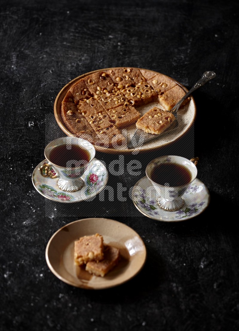 Basbousa with tea in a dark setup