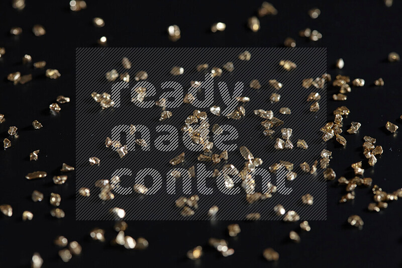 Gold shimmering fragments of glass scattered on a black background