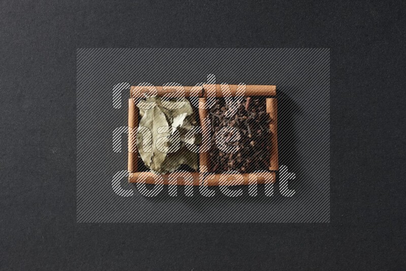 2 squares of cinnamon sticks full of cloves and bay laurel leaves on black flooring