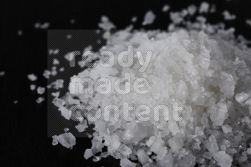 A bunch of coarse sea salt crystals on black background