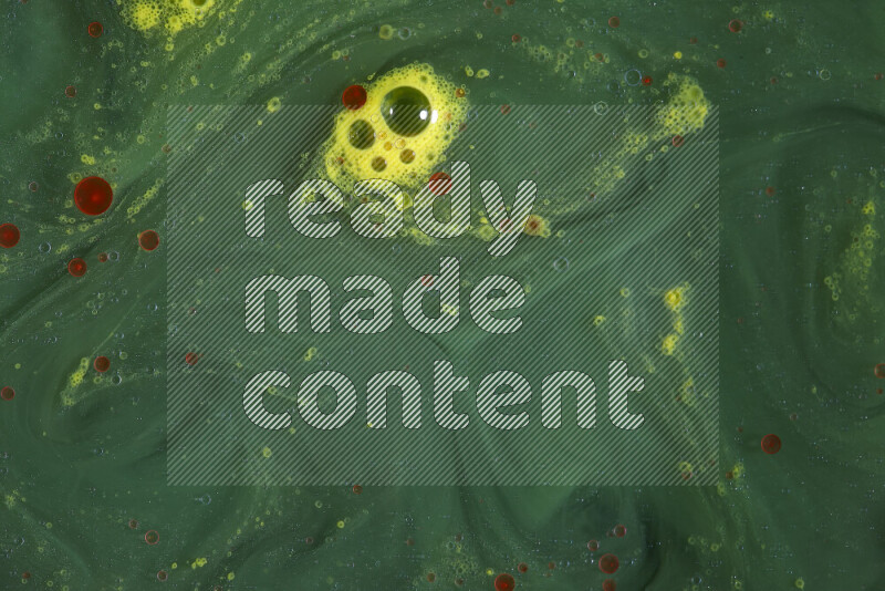 The image captures a dramatic splatter of red, green and yellow paints over the backdrop