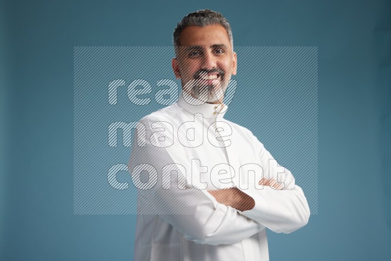 Saudi man waring thob posing to the camera on blue background