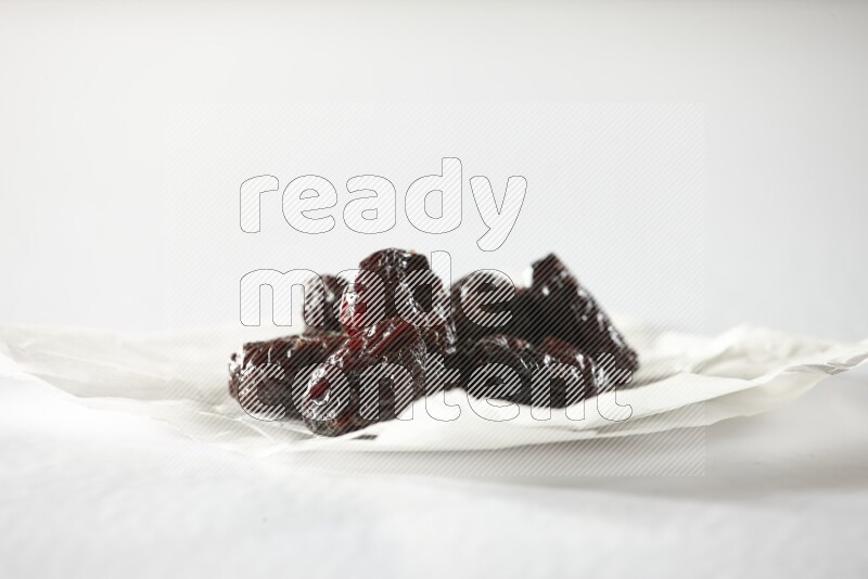 Dried plums on a crumpled piece of paper on a white background in different angles