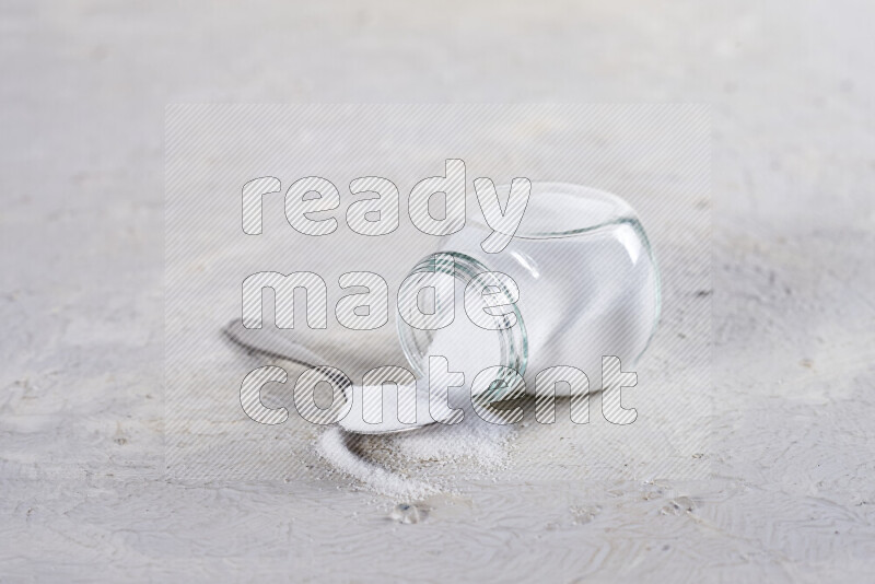 A glass jar full of fine table salt on white background