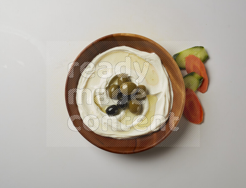 Lebnah garnished with whole olives in a wooden plate on a white background