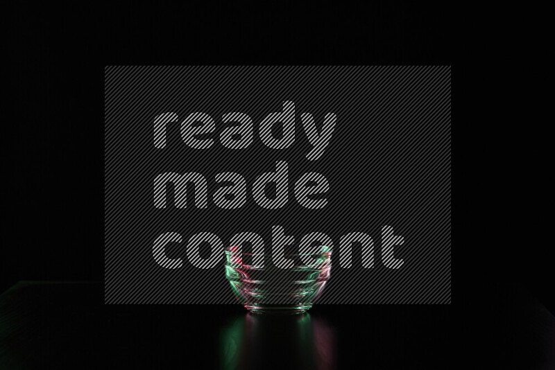 Glassware with rim light in red and green against black background