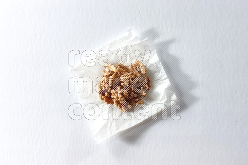 Peeled walnuts on a crumpled piece of paper on a white background in different angles