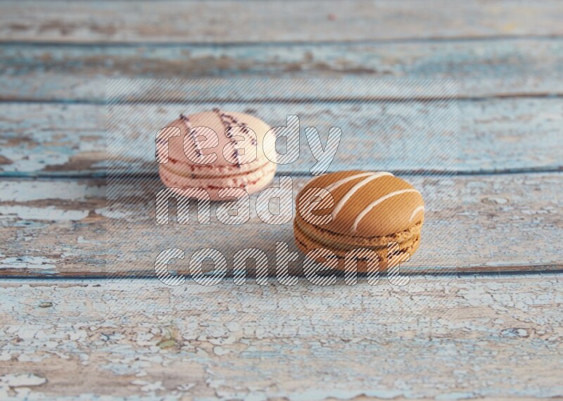 45º Shot of of two assorted Brown Irish Cream, and pink orange blossom  macarons on light blue background