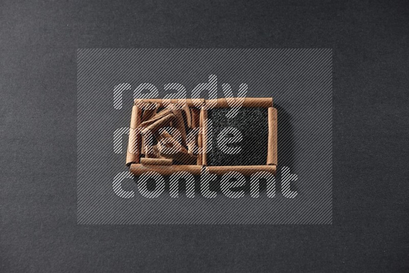 2 squares of cinnamon sticks full of black seeds and cinnamon on black flooring