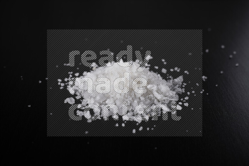 A bunch of coarse sea salt crystals on black background