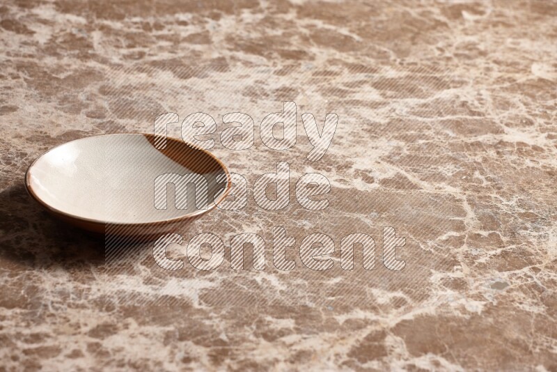 A multicolored pottery plate on beige marble background