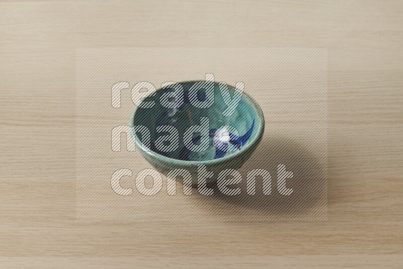 A decorative pottery bowl on light wooden background
