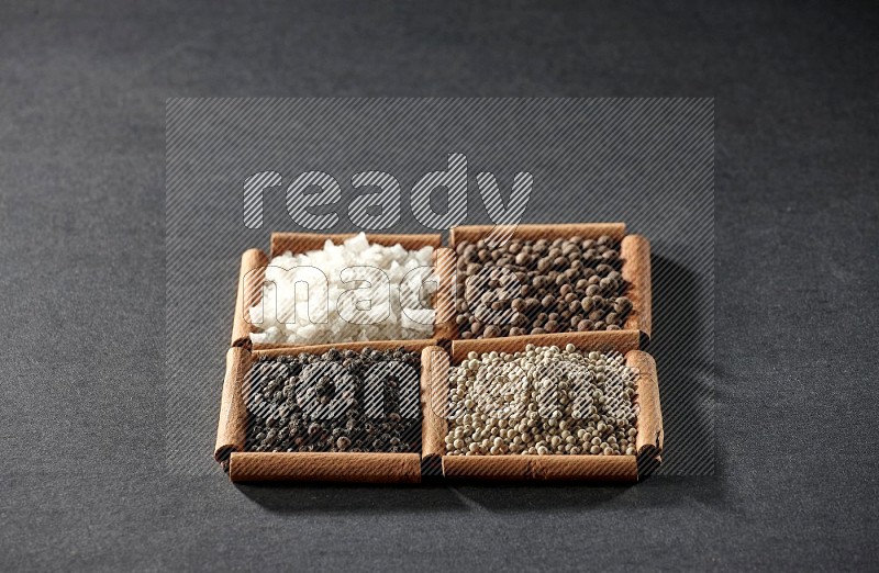 4 squares of cinnamon sticks full of black pepper, white pepper, allspice and white salt on black flooring