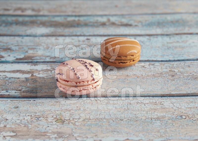 45º Shot of of two assorted Brown Irish Cream, and pink orange blossom  macarons on light blue background