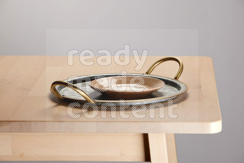 multicolored plate placed on a rounded stainless steel tray with golden handels on the edge of wooden table