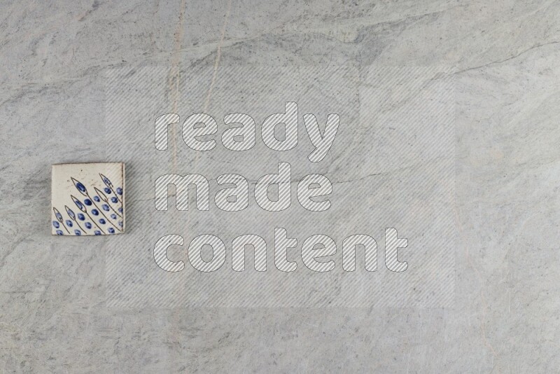 A decorative pottery coaster on grey marble background