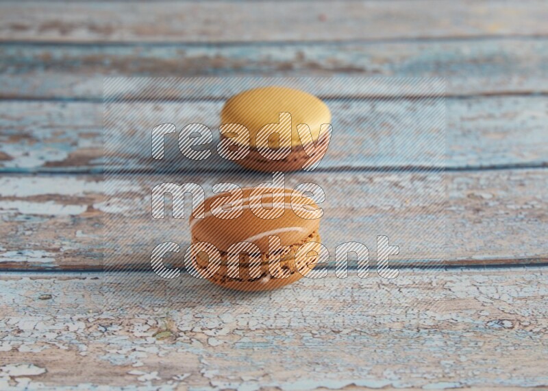 45º Shot of of two assorted Brown Irish Cream, and Yellow, and Brown Chai Latte macarons  on light blue background