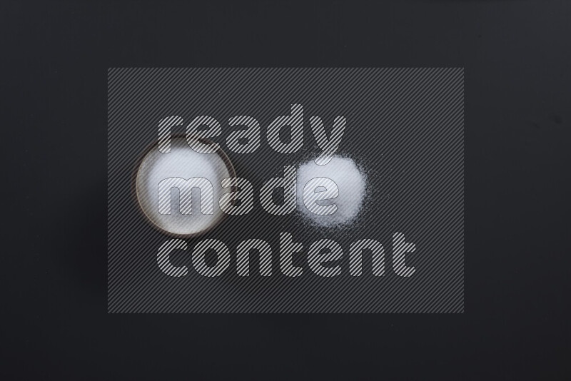 Pottery bowl full of fine table salt and coarse sea salt on black background