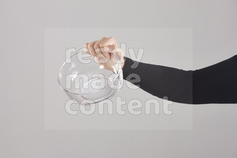 A woman in black abaya holding different glassware in different positions