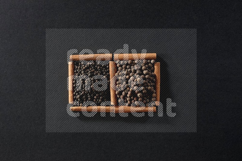 2 squares of cinnamon sticks full of black peppers and allspice on black flooring