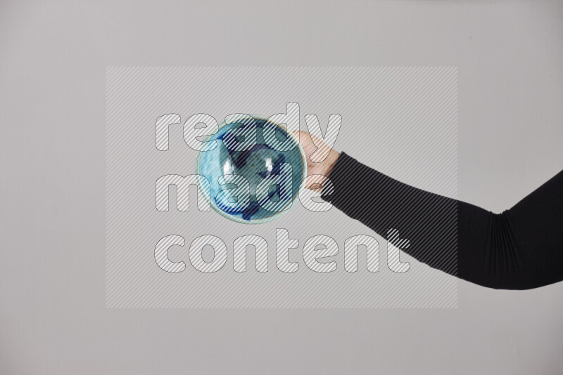 A woman in black abaya holding different pottery essentials in different positions