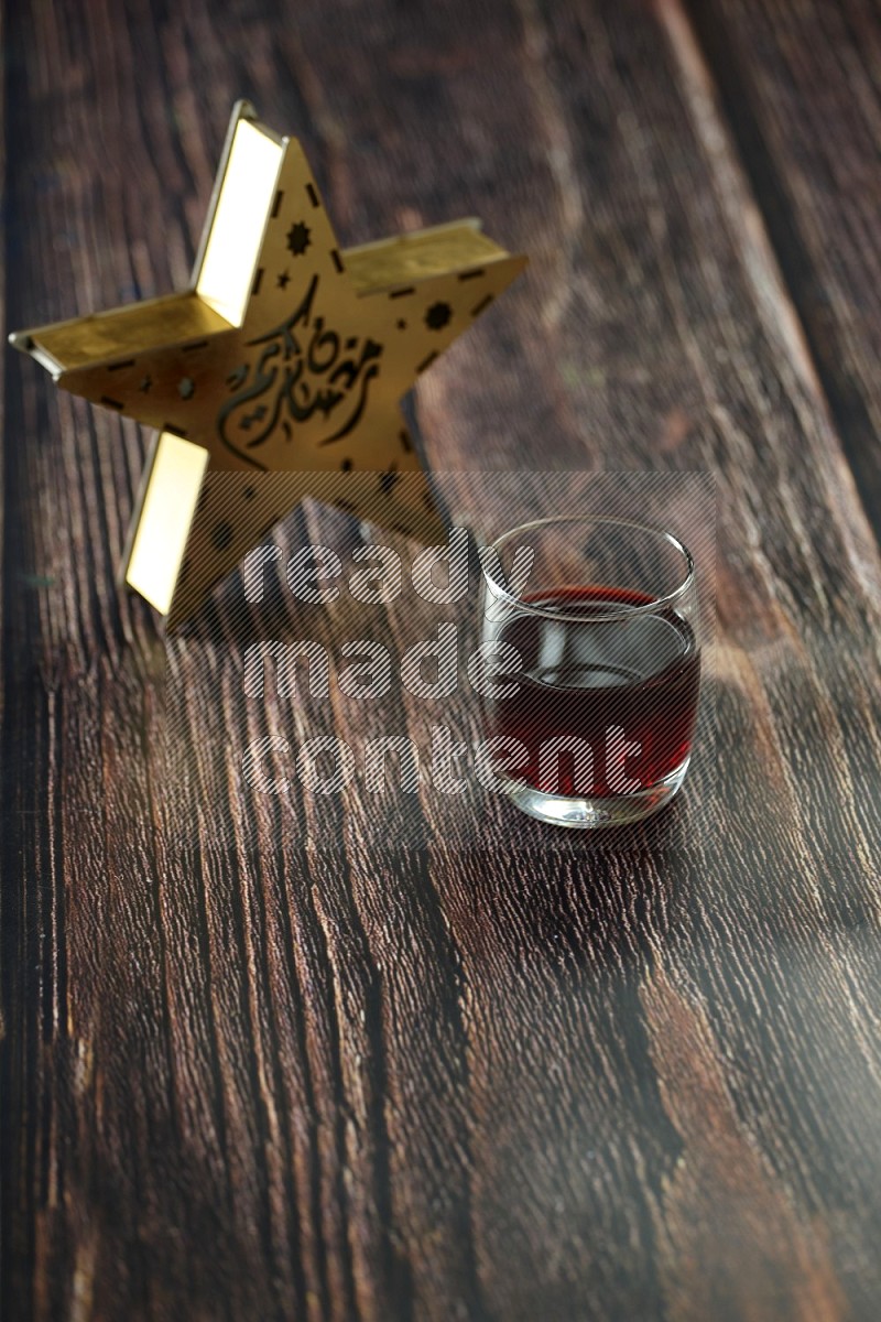 A wooden golden star lantern with different drinks, dates, nuts, prayer beads and quran on brown wooden background