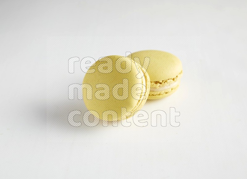 45º Shot of two Yellow Lime macarons on white background