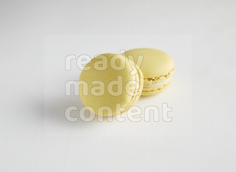 45º Shot of two Yellow Lime macarons on white background
