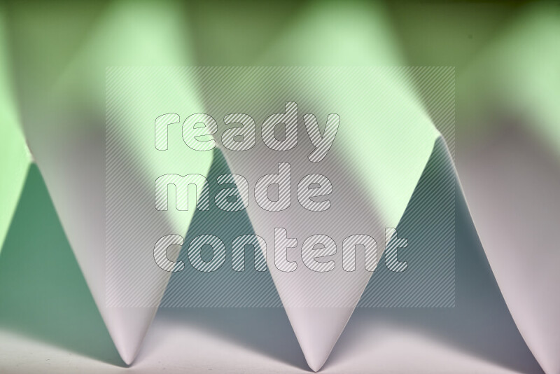 A close-up abstract image showing sharp geometric paper folds in white and green gradients