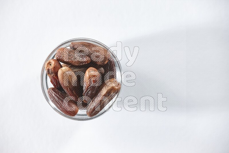 A glass bowl full of dried dates on a white background in different angles