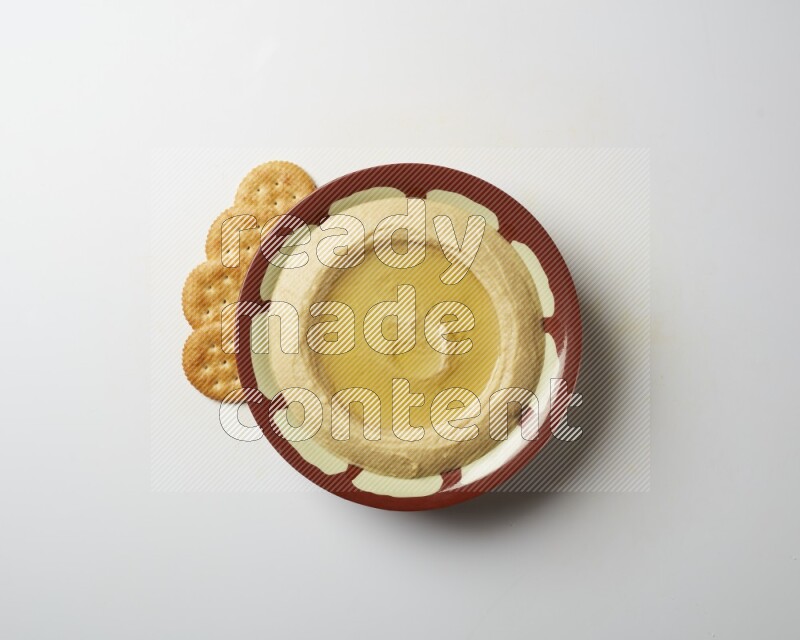 Hummus in a traditional plate garnished with olive oil on a white background